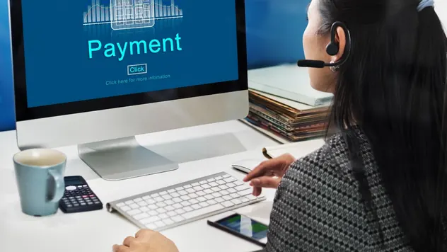 Business owner reviewing a payment screen on a desktop computer while working through invoices
