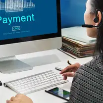 Business owner reviewing a payment screen on a desktop computer while working through invoices