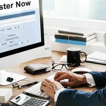 Business owner filling in an online registration form on a desktop computer at an office desk
