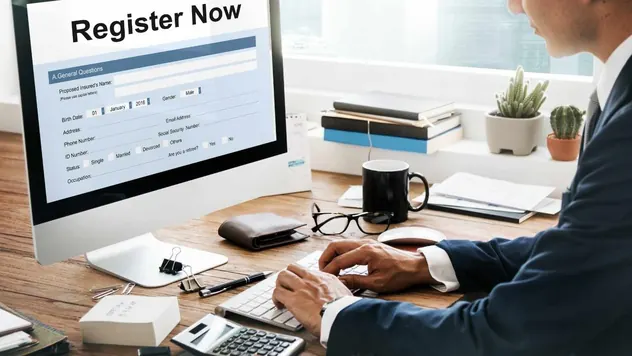 Business owner filling in an online registration form on a desktop computer at an office desk